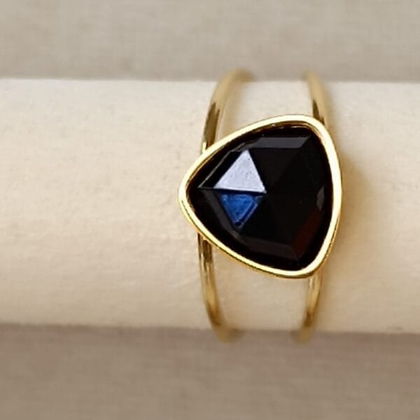 Anillo ERYNA dorado con piedra negra sobre soporte