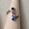 Anillo ERYNA de acero con piedras de color – Vista sobre soporte Anillo de acero ERYNA con piedras decorativas de colores sobre soporte cónico