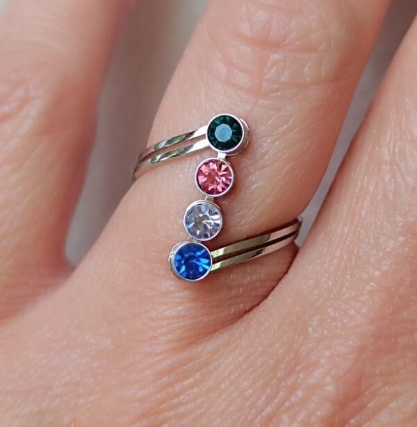 Anillo ERYNA de acero con piedras de color – Puesto en mano Anillo abierto ERYNA con piedras de colores brillantes colocado en dedo femenino