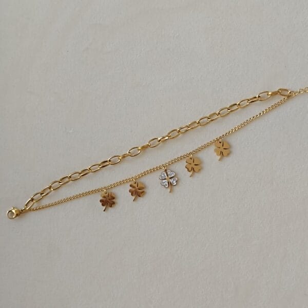 Pulsera ERYNA dorada con dos cadenas y colgantes de tréboles extendida