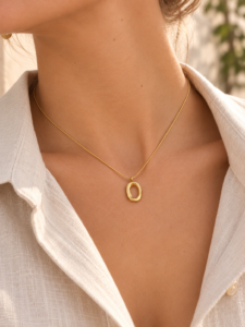 Collar dorado con colgante ovalado irregular sobre cuello de mujer
