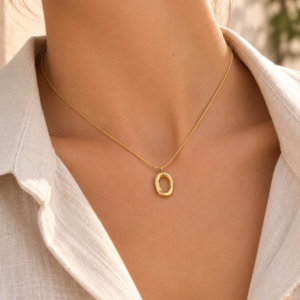 Collar dorado con colgante ovalado irregular Collar dorado con colgante ovalado irregular sobre cuello de mujer