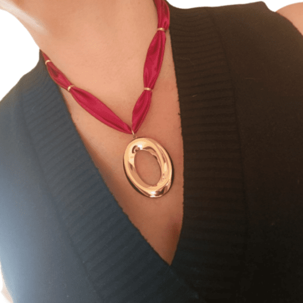 Collar ERYNA elipse dorada puesto en cuello de mujer