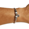 Pulsera rígida de acero inoxidable plateada con circonitas y charm de trébol en la muñeca