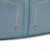 Detalle de costuras y remaches en bandolera azul claro efecto piel
