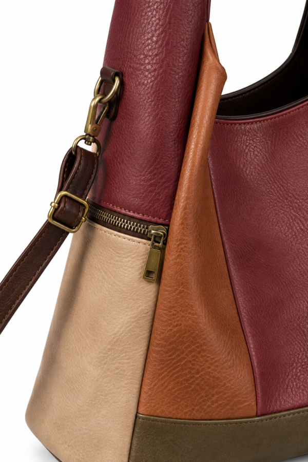 Bolso MAC&NOA MDX260343 - detalle de la bandolera y cremallera Detalle del bolso MAC&NOA MDX260343 con correa bandolera, herrajes y cremallera sobre paneles burdeos y beige