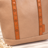 Detalle de las asas del bolso tote con troquelado floral y remaches dorados
