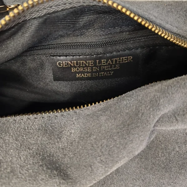 Interior forrado en negro del bolso de ante con bolsillo con cremallera y etiqueta Made in Italy