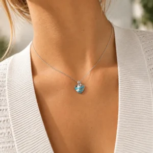 Mujer con collar de cadena plateada y colgante de corazón con rayas turquesa en acero inoxidable
