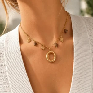 Collar ERYNA colgante ovalado con charms puesto Mujer con collar ERYNA dorado con charms, piedras ámbar y colgante ovalado de acero