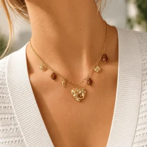 Mujer con collar ERYNA dorado con charms, piedras ámbar y colgante de corazón martillado