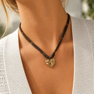 Mujer con collar ERYNA de cinta textil oscura y colgante de corazón dorado martillado