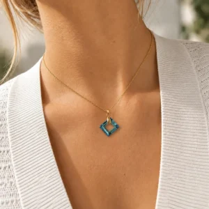 Collar ERYNA cuadrado geométrico con cristal puesto Mujer con collar ERYNA de cadena dorada y colgante cuadrado de cristal azul