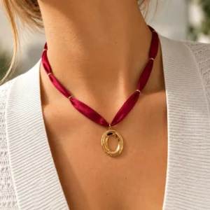 Collar ERYNA elipse dorada con cinta textil puesto Mujer con collar ERYNA de cinta textil roja y colgante de elipse dorada