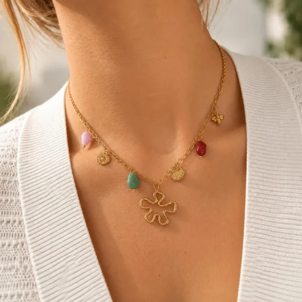 Collar ERYNA flor orgánica con piedras puesto Mujer con collar ERYNA dorado con piedras de colores, charms y colgante de flor orgánica