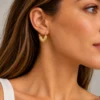 Mujer con pendiente de aro en forma de corazón dorado martelado en acero inoxidable ERYNA
