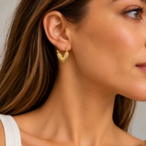 Mujer con pendiente de aro en forma de corazón dorado martelado en acero inoxidable ERYNA