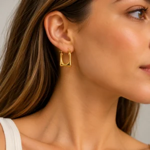 Mujer con pendiente de aro cuadrado dorado en acero inoxidable ERYNA