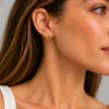 Mujer con pendiente de presión en forma de corazón calado dorado en acero inoxidable ERYNA