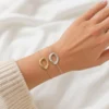 Pulsera círculo de acero ERYNA dorada y plateada puesta en la muñeca Pulsera círculo de acero ERYNA dorada y plateada puesta en la muñeca