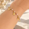 Muñeca con pulsera dorada de perlas y mariposas colgantes en acero inoxidable ERYNA