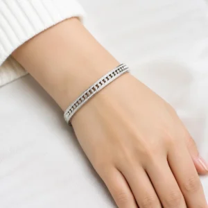 Pulsera ERYNA rígida de acero inoxidable con cadena y circonitas puesta en la muñeca