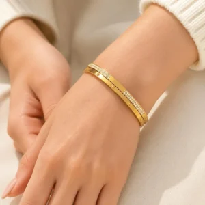 Pulsera rígida ERYNA de acero inoxidable dorada con circonitas puesta en la muñeca