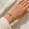 Pulsera rígida dorada ERYNA con piedras de colores puesta en la muñeca