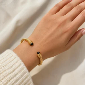 Pulsera rígida dorada ERYNA con piedras de colores puesta en la muñeca