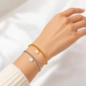 Pulsera ERYNA de acero inoxidable con trébol dorada y plateada puesta en la muñeca