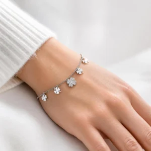 Pulsera de acero inoxidable con tréboles y flor de circonitas puesta en la muñeca